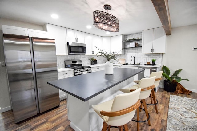 kitchen featuring hanging light fixtures, white cabinets, stainless steel appliances, and beamed ceiling