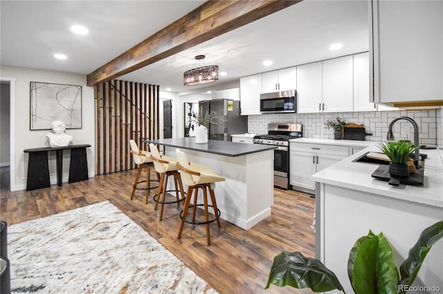 kitchen featuring tasteful backsplash, stainless steel appliances, sink, beamed ceiling, and white cabinetry