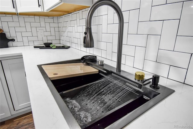 interior details with light stone countertops, sink, and tasteful backsplash