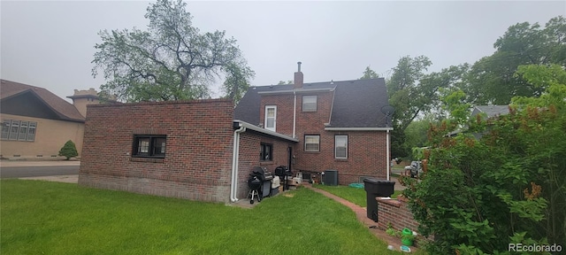 200 W 5th St, Julesburg, CO 80737 - rear view of house with brick siding, central air condition unit, a yard, and a chimney