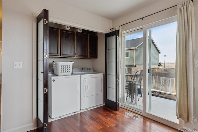 washroom featuring washing machine and clothes dryer, dark hardwood / wood-style flooring, and cabinets