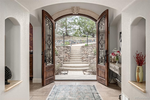 648 Ruby Trust Dr, Castle Rock, CO 80108 - entrance foyer with arched walkways, a textured wall, and stone tile flooring