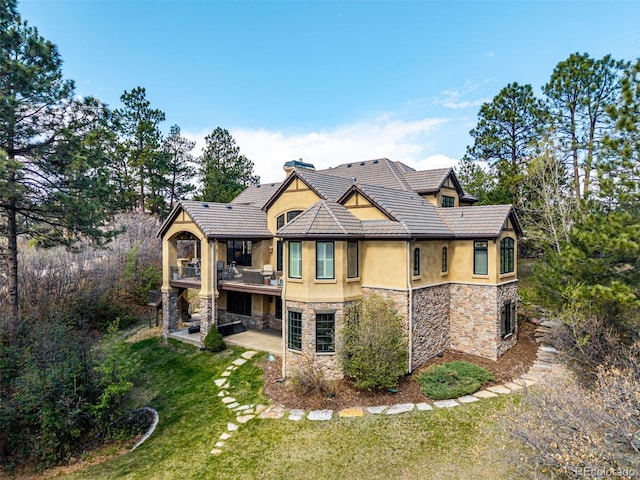 648 Ruby Trust Dr, Castle Rock, CO 80108 - back of property featuring stucco siding, stone siding, a lawn, a patio area, and a balcony