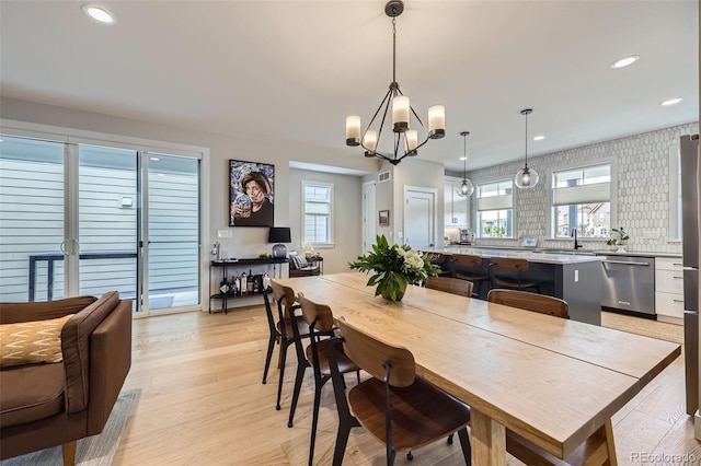 dining room with healthy amount of natural light, a chandelier, recessed lighting, and light wood-type flooring