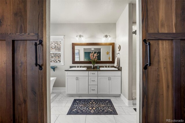 20243 High Pines Dr, Monument, CO 80132 - bathroom with double vanity, marble finish flooring, a freestanding tub, and baseboards