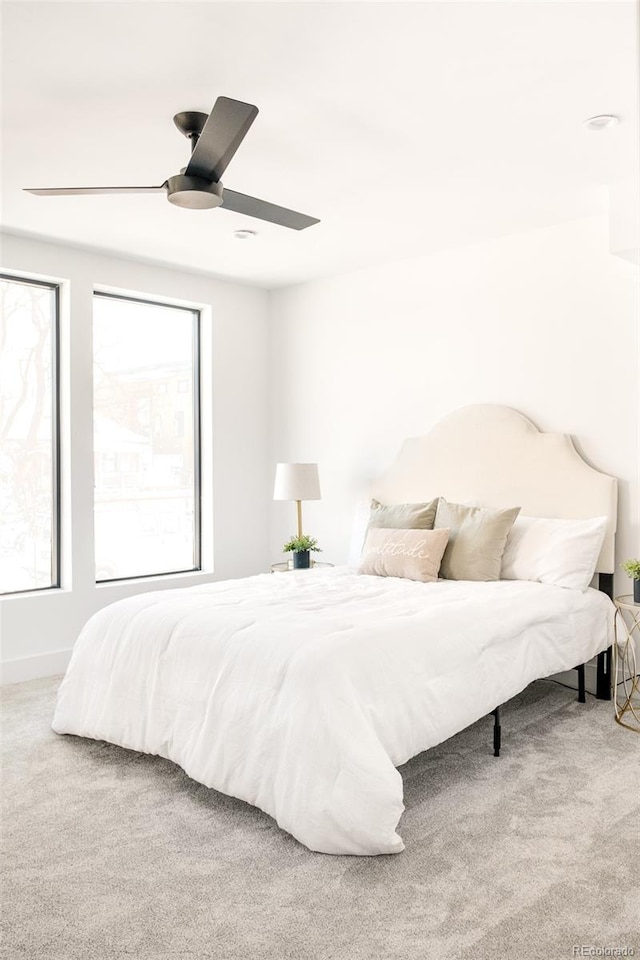 carpeted bedroom featuring multiple windows and ceiling fan