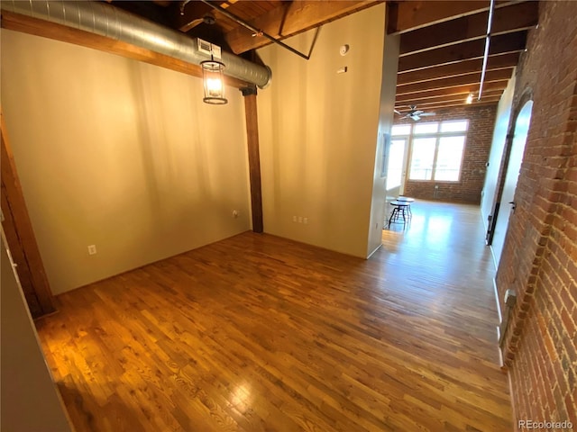 basement featuring brick wall, hardwood / wood-style floors, and ceiling fan