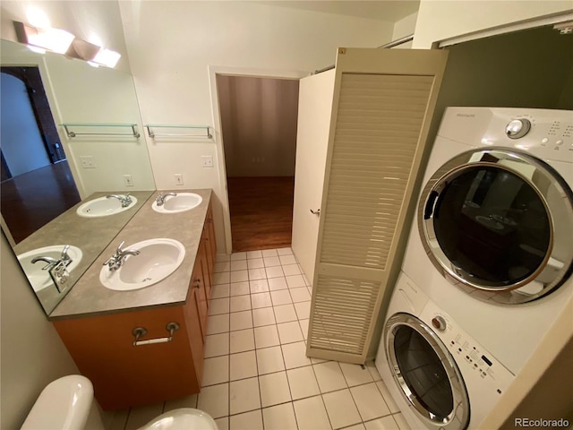 bathroom with stacked washer / drying machine, tile patterned flooring, and vanity