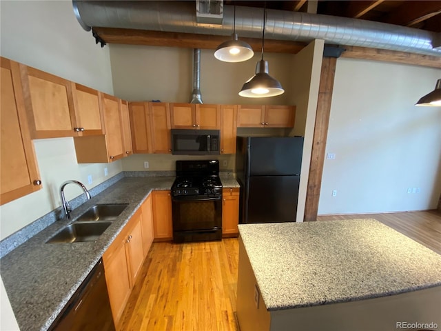 kitchen featuring sink, hanging light fixtures, a high ceiling, black appliances, and light hardwood / wood-style flooring