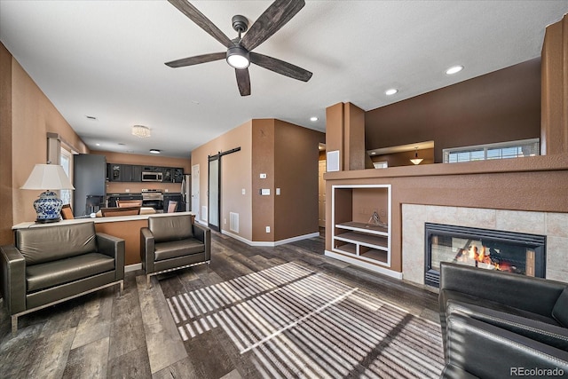 2404 S Genoa Way, Aurora, CO 80013 - living room featuring a barn door, dark wood finished floors, ceiling fan, a fireplace, and baseboards