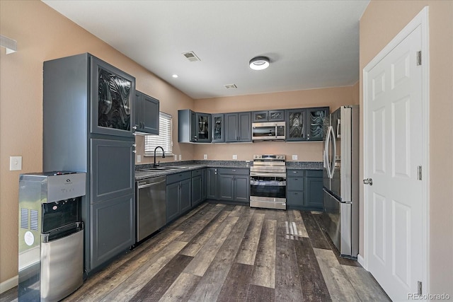 2404 S Genoa Way, Aurora, CO 80013 - kitchen with appliances with stainless steel finishes, dark wood finished floors, glass insert cabinets, and a sink