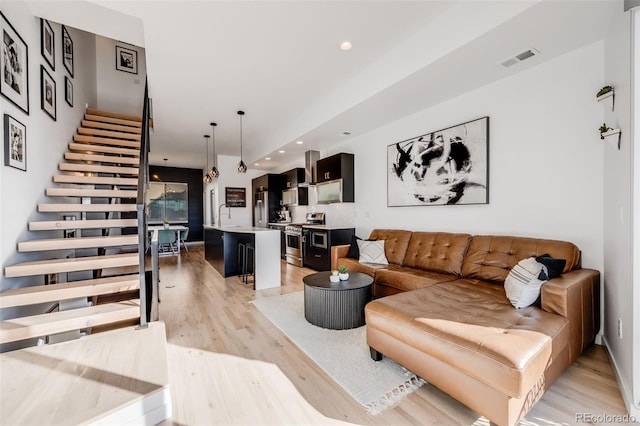 living room featuring stairway, recessed lighting, visible vents, and light wood-style floors