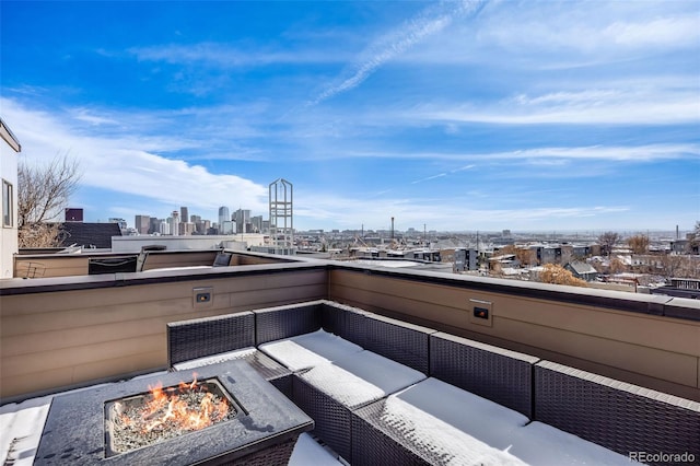 view of patio with a balcony, a city view, and an outdoor living space with a fire pit