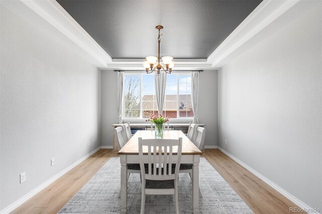 17378 W 78th Dr, Arvada, CO 80007 - dining area with a tray ceiling, a chandelier, light wood-type flooring, and baseboards