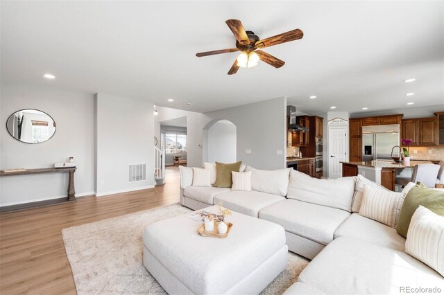 17378 W 78th Dr, Arvada, CO 80007 - living room featuring light wood-type flooring, arched walkways, recessed lighting, a ceiling fan, and baseboards