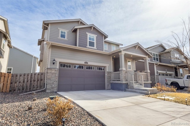 craftsman house featuring a garage, concrete driveway, stone siding, and fence