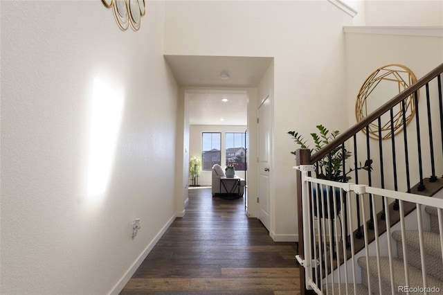 hallway with stairs, baseboards, and dark wood-type flooring