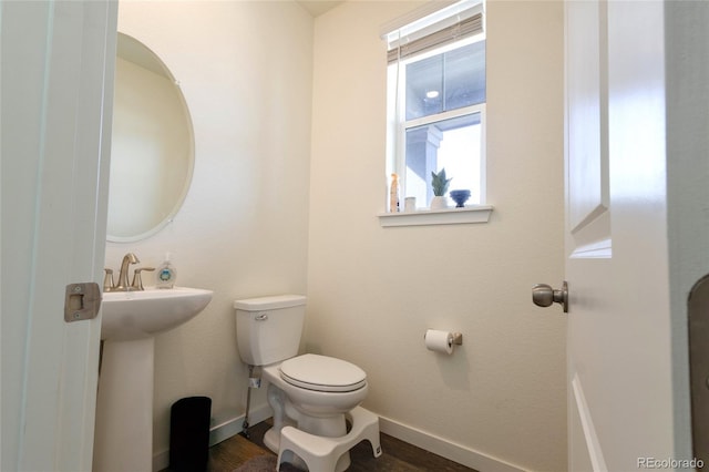 half bathroom with a sink, toilet, and baseboards