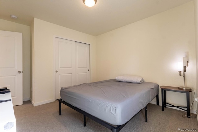 bedroom featuring light carpet, a closet, and baseboards