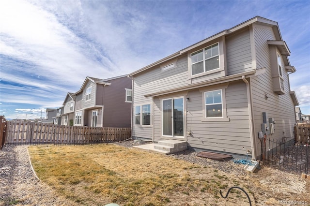 back of property featuring entry steps, fence private yard, and a lawn