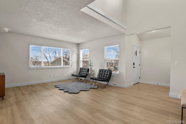 unfurnished room with a skylight, light hardwood / wood-style flooring, and a textured ceiling