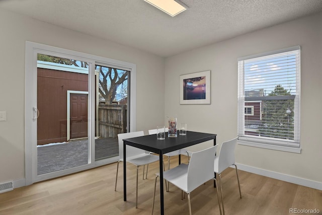 dining area with a textured ceiling and light hardwood / wood-style flooring