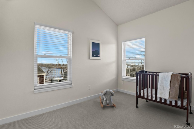 bedroom with a crib, vaulted ceiling, and carpet floors