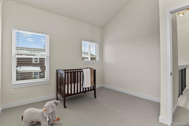 bedroom with a nursery area, vaulted ceiling, and light carpet