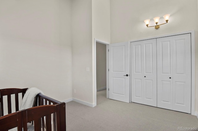 bedroom featuring a nursery area, light colored carpet, and a closet