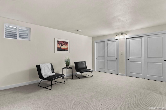 living area featuring light colored carpet and a textured ceiling