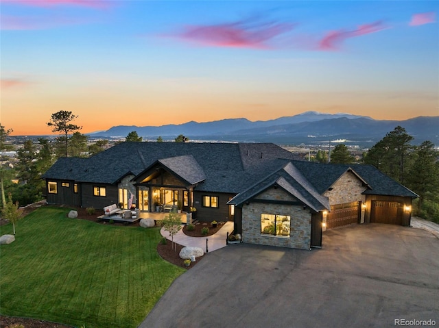 view of front of property featuring a garage, a mountain view, and a lawn