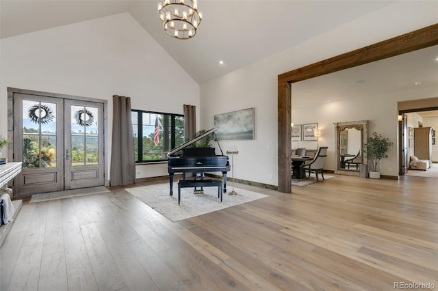 entrance foyer featuring french doors, a chandelier, high vaulted ceiling, and light wood-type flooring