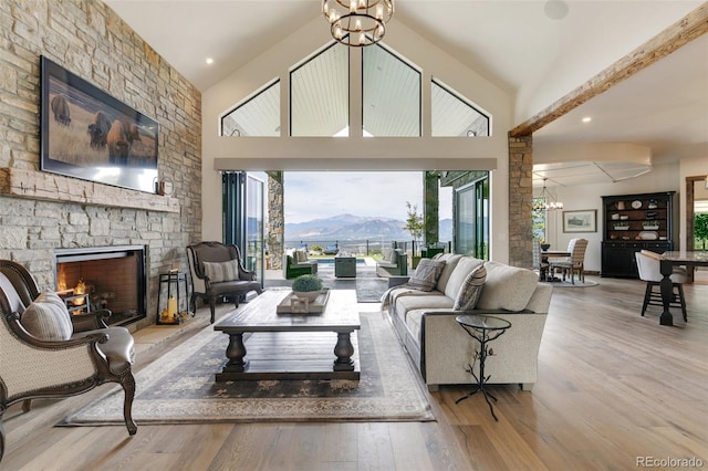 living room with high vaulted ceiling, a mountain view, a fireplace, and light hardwood / wood-style floors