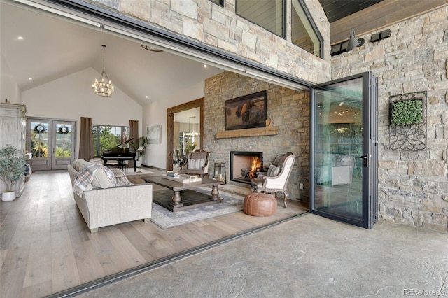 living room with an inviting chandelier, hardwood / wood-style flooring, high vaulted ceiling, and a fireplace