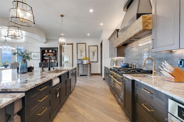 kitchen featuring custom exhaust hood, stainless steel appliances, light wood-type flooring, and pendant lighting