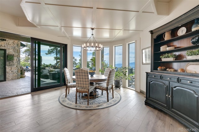 dining area with coffered ceiling, light hardwood / wood-style flooring, and an inviting chandelier