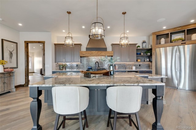 kitchen with a large island, stainless steel fridge, light wood-type flooring, and pendant lighting