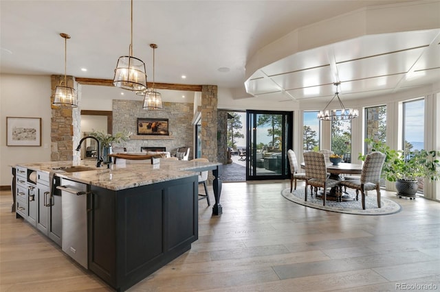 kitchen featuring a wealth of natural light, a large island, a stone fireplace, and decorative light fixtures