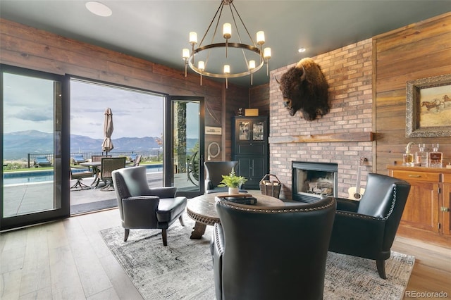 living room featuring light hardwood / wood-style flooring, a mountain view, wooden walls, and a fireplace