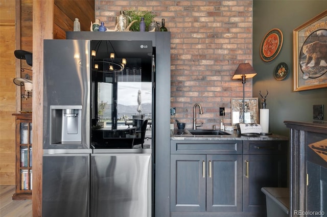 kitchen with stainless steel fridge, hardwood / wood-style flooring, dark stone countertops, gray cabinetry, and sink