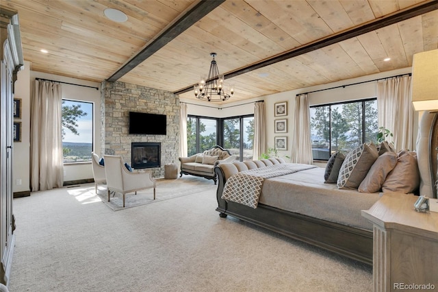 bedroom with a chandelier, a stone fireplace, multiple windows, and light colored carpet