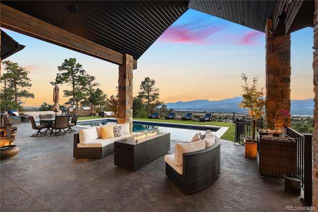 patio terrace at dusk featuring an outdoor living space with a fire pit and a mountain view