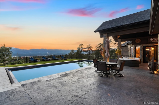 pool at dusk featuring a patio area