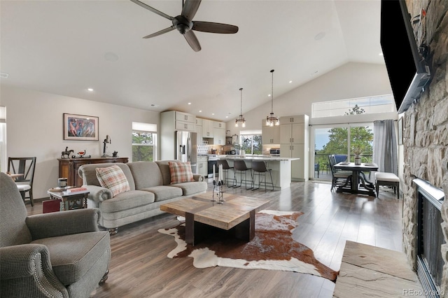 living room featuring hardwood / wood-style flooring, ceiling fan, a fireplace, and vaulted ceiling