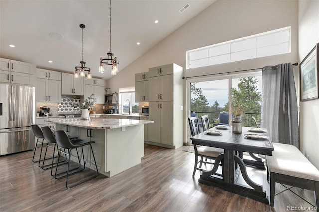 kitchen featuring a healthy amount of sunlight, stainless steel appliances, a kitchen island, and hanging light fixtures