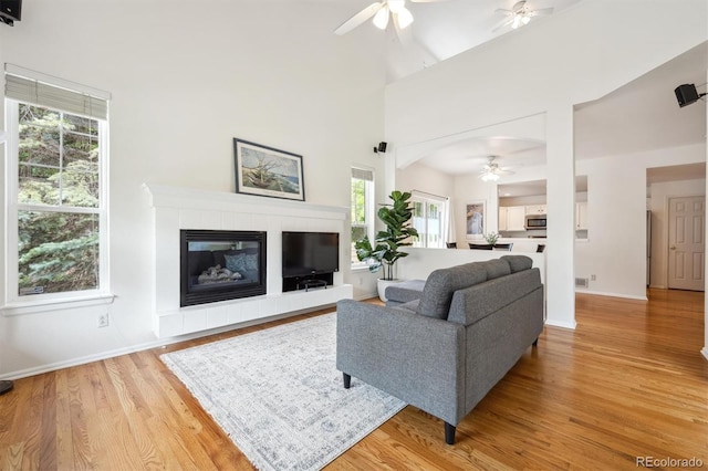 10166 Grove Loop Unit D, Westminster, CO 80031 - living room with ceiling fan, light wood-style flooring, baseboards, a fireplace, and a high ceiling