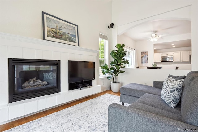 10166 Grove Loop Unit D, Westminster, CO 80031 - living room with ceiling fan, wood finished floors, a tiled fireplace, and arched walkways