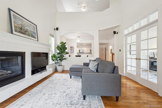 10166 Grove Loop Unit D, Westminster, CO 80031 - living room featuring a ceiling fan, a tile fireplace, wood finished floors, and a towering ceiling