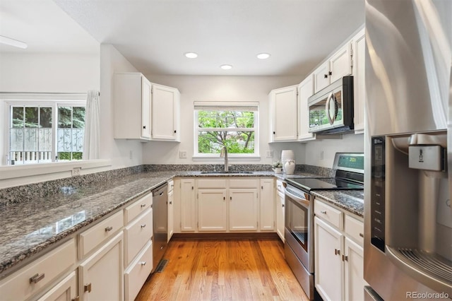 10166 Grove Loop Unit D, Westminster, CO 80031 - kitchen with appliances with stainless steel finishes, a sink, dark stone countertops, light wood-style floors, and recessed lighting