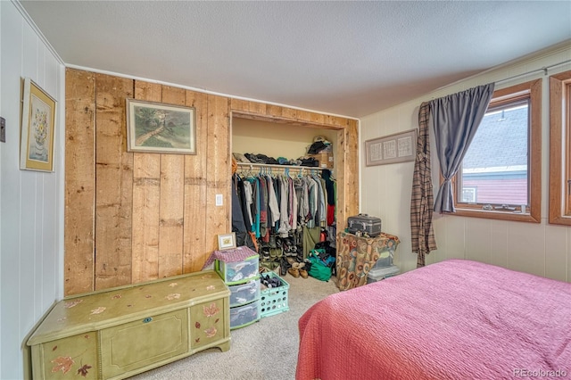 bedroom with a walk in closet, a closet, a textured ceiling, and carpet flooring